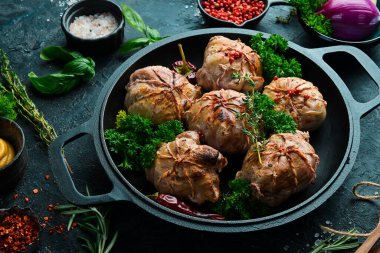 Izgara Sulu Hindi Pirzolası. Baharat ve otlarla dolu bir tavada. Siyah taştan bir arka planda. Üst görünüm.