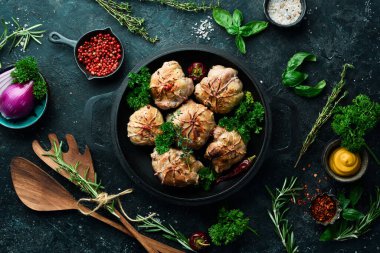 Izgara Sulu Hindi Pirzolası. Baharat ve otlarla dolu bir tavada. Siyah taştan bir arka planda. Üst görünüm.