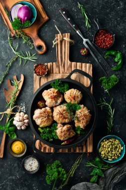 Izgara Sulu Hindi Pirzolası. Baharat ve otlarla dolu bir tavada. Siyah taştan bir arka planda. Üst görünüm.