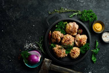 Izgara Sulu Hindi Pirzolası. Baharat ve otlarla dolu bir tavada. Siyah taştan bir arka planda. Üst görünüm.