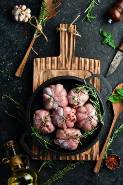 Hindili filetoya sarılı hindi pirzolası, pişmeye hazır. Barbekü. Siyah beton bir arka planda. Üst görünüm.
