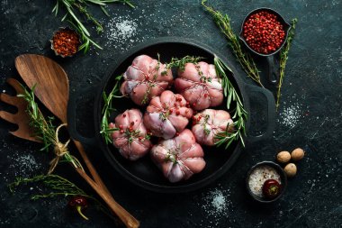 Hindili filetoya sarılı hindi pirzolası, pişmeye hazır. Barbekü. Siyah beton bir arka planda. Üst görünüm.