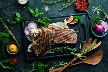 Baharatlı ve biberiyeli ızgara biftek. Siyah beton bir arka planda. Yan görünüm.