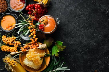 Reçel. Viburnum böğürtlen ve ballı deniz dikeni. Karanlık bir arka planda yüksek içerikli C vitamini içeren yiyecekler. en üstteki görünüm