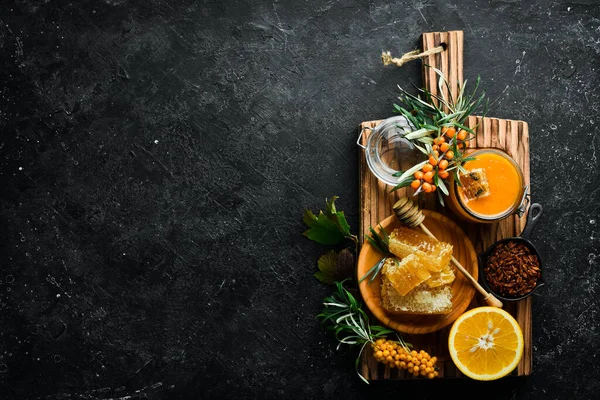 Sonbahar menüsü konsepti. Tatlım, deniz dikenleri ve turunçgiller. Karanlık bir arka planda. Üst görünüm.