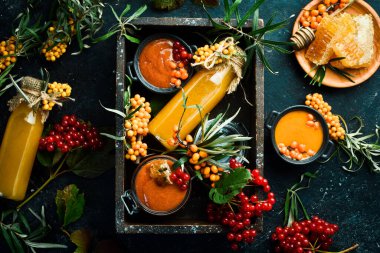 Ballı, deniz dikenli ve C vitaminli bir şişe ev yapımı içecek. Sonbahar içecekleri. Karanlık bir arka planda. Üst görünüm.