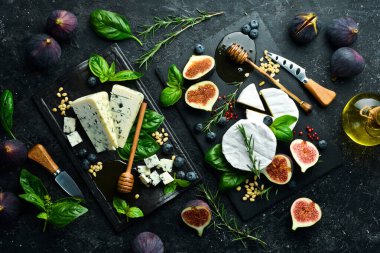 Taş tabaklar üzerinde peynir ve atıştırmalıklar. Üst Manzara. Siyah bir arkaplanda.