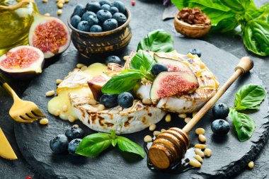 İncir, bal ve yaban mersinli peynirli peynir. Tabakta. Gri beton arka planda.