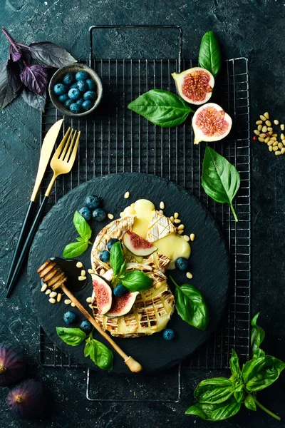 イチジク 蜂蜜とブルーベリーとベイクドブリーチーズ 皿の上だ 黒石の背景に — ストック写真