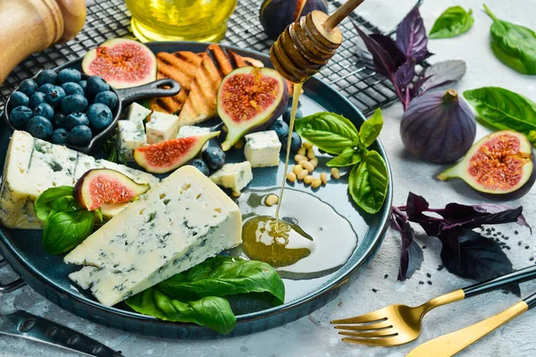 传统的蓝奶酪 无花果 蓝莓和蜂蜜放在盘子里 在一个具体的背景 侧视图 — 图库照片