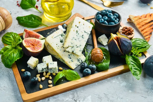 传统的蓝奶酪 无花果 蓝莓和蜂蜜放在盘子里 在一个具体的背景 侧视图 — 图库照片