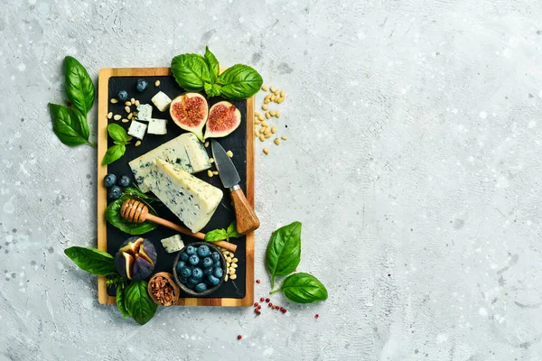 切碎的奶酪在木板上 蓝奶酪 无花果 蓝莓和蜂蜜 在一个具体的背景 顶部视图 — 图库照片