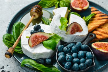 Brie peyniri, ballı ve incirli, yan manzara. Beton bir arka planda.