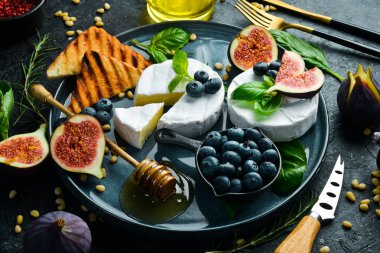 Brie peyniri, ballı ve incirli, yan manzara. Beton bir arka planda.