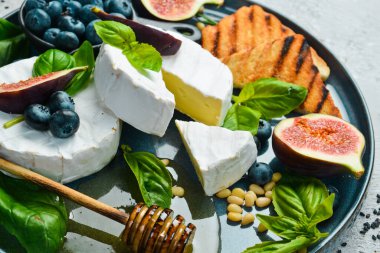 Brie cheese, with honey and figs, side view. On a concrete background. clipart