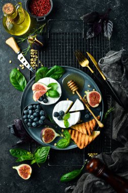 Brie peynirli bir tabak, ballı ve incirli. Beton bir arka planda. Üst görünüm.