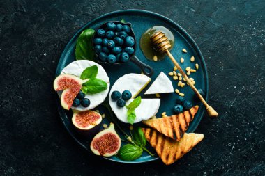 Brie peynirli bir tabak, ballı ve incirli. Beton bir arka planda. Üst görünüm.