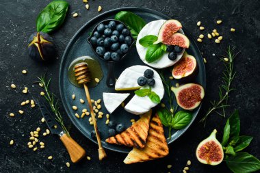 Brie peynirli bir tabak, ballı ve incirli. Beton bir arka planda. Üst görünüm.