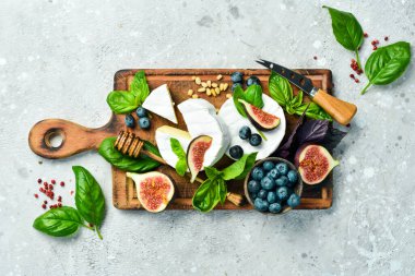 Ballı peynir ve tahtanın üzerinde incir. Beton bir arka planda. Üst görünüm.