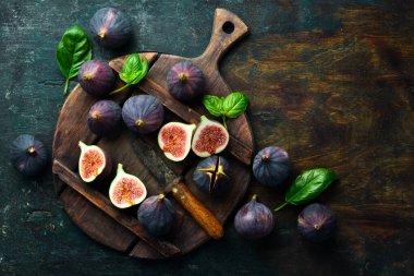 Taze incir, yeşil yaprak ve siyah masa arka planında. Mesaj için yer var. Üst görünüm.