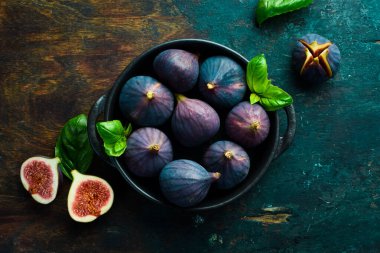 Bir kase taze incir. Taze tropikal meyveler. Karanlık bir arka planda. Metin için boşluk.