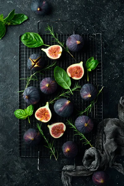 Figs and leaves on a dark stone table. On a dark background. Space for text. Top view.