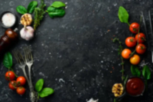 Defocused food background. Black stone cooking background. Spices and vegetables. Top view. Free space for your text.