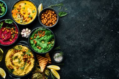 Renkli humus kaseleri arka planda. Farklı daldırma çeşitleri. Geleneksel humus, bitki humusu, pancar humusu. Beton bir arka planda.