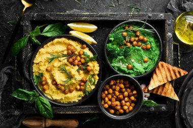 Yeşil bezelyeli humus ve içinde zeytin yağı olan nohut. Beton bir arka planda.