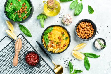 Yeşil bezelyeli humus ve içinde zeytin yağı olan nohut. Beton bir arka planda.