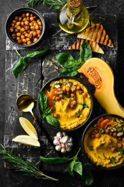 Nohut ve balkabağından, zeytinyağı ve baharatlı humus. Sağlıklı vejetaryen yemekleri. Siyah bir arkaplanda.