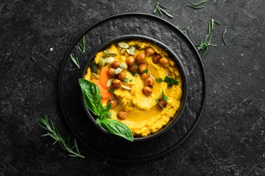 Nohut ve havuçtan yapılmış humus, zeytin yağı ve baharatla birlikte. Üst Manzara. Siyah bir arkaplanda.