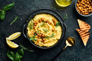 Kavanozda nohut olan geleneksel vejetaryen humus. Üst Manzara. Siyah taştan bir arka planda.