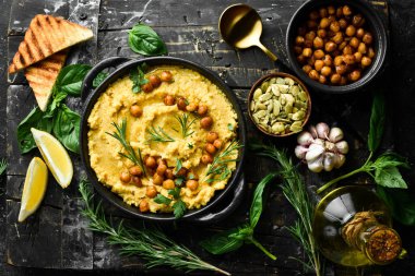 Siyah bir tabakta nohut ve biberiyeli humus. Vejetaryen yemeği. Üst Manzara. Siyah taştan bir arka planda.