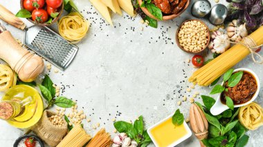 Pişirme geçmişi: pesto sosu, makarna, fesleğen, parmesan ve fındık, zeytinyağı. Beton bir arka planda.