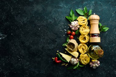 İtalyan mutfağı geçmişi: makarna, fesleğen, parmesan, pesto, domates ve fındık, zeytinyağı. Siyah taş arka planda.