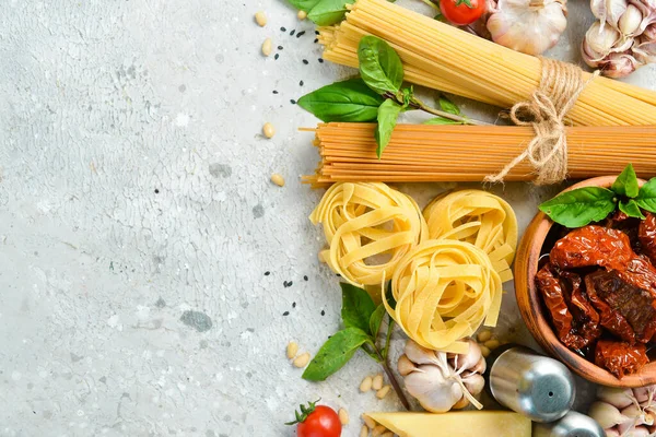 Food banner. Italian traditional cuisine: pesto sauce, pasta, basil, parmesan and nuts, olive oil. On a concrete background. Top view.