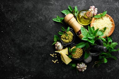 Pesto sosu. Pesto yapmak için gerekli malzemeler. Siyah taştan bir arka planda. Üst görünüm.
