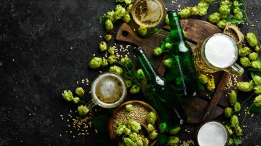 Taze zıpla, bardaklar ve bira. Siyah bir arka planda cam şişelerde hafif bira. Bira afişi.