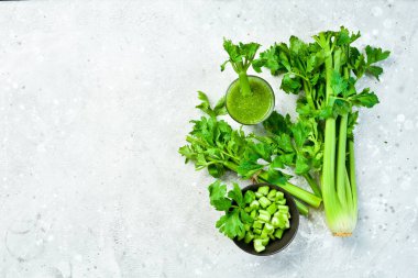 Gri taş zemin üzerinde yeşil kereviz sapı ve kereviz suyu. Vejetaryen içeceği. Metin için boş alan.