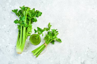 Gri taş zemin üzerinde yeşil kereviz sapı ve kereviz suyu. Vejetaryen içeceği. Metin için boş alan.