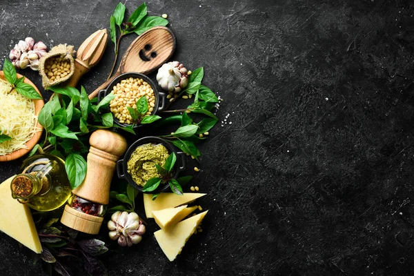 Pesto sosu. Pesto yapmak için gerekli malzemeler. Siyah taştan bir arka planda. Üst görünüm.