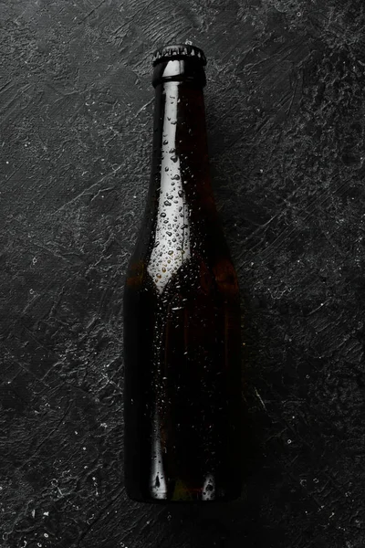 Fresh hop, glasses and beer. Dark beer in glass bottles on a black stone background. Beer banner.