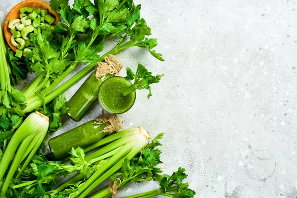 Gri taş zemin üzerinde yeşil kereviz sapı ve kereviz suyu. Vejetaryen içeceği. Metin için boş alan.
