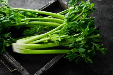 Tahta bir kutuda yaprakları olan taze kereviz sapı. Taş zeminde organik sağlıklı yiyecekler. Üst Manzara. Metin için boş alan.