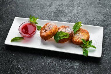 Tatlı. Ahududu soslu ve pudra şekerli peynirli krep. Siyah taştan bir arka planda.