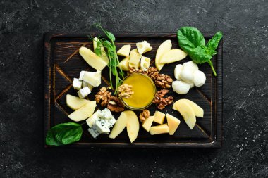 Peynir yaylası. Sert peynir, feta, mavi peynir ve peynir. Siyah taştan bir arka planda.