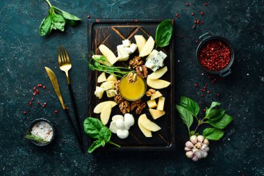 Peynir yaylası. Sert peynir, feta, mavi peynir ve peynir. Siyah taştan bir arka planda.