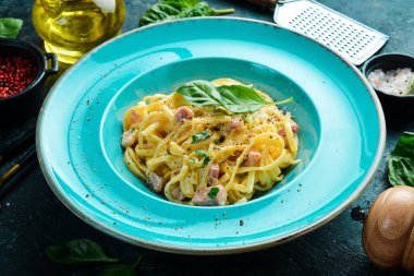 Pastırmalı, peynirli ve fesleğenli makarna. İtalyan yemeği. Siyah taştan bir arka planda.