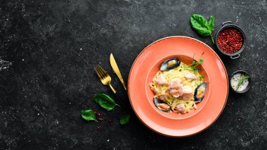 Deniz ürünleri. Karides, midye, peynir ve fesleğenli makarna. İtalyan yemeği. Siyah taştan bir arka planda.